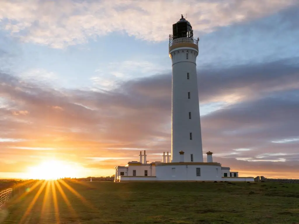 a lighthouse on a field with the sunset in the background at Apartment Harbour Nights 4 by Interhome in Lossiemouth