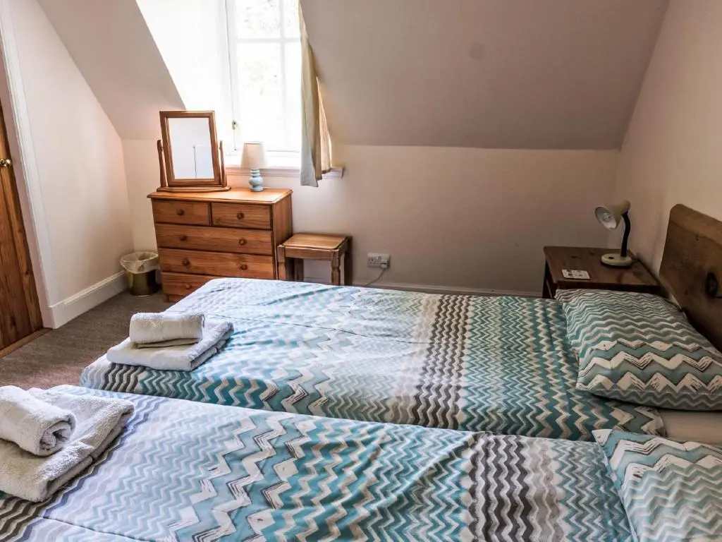 a bedroom with two beds and a dresser with a mirror at Holiday Home Old Stables by Interhome in Drumnadrochit