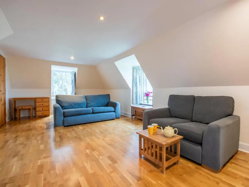 a living room with two blue couches and a table at Holiday Home Old Stables by Interhome in Drumnadrochit