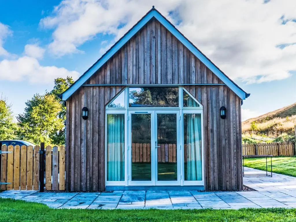 a wooden shed with a glass door at Holiday Home The Barn by Interhome in Drumnadrochit