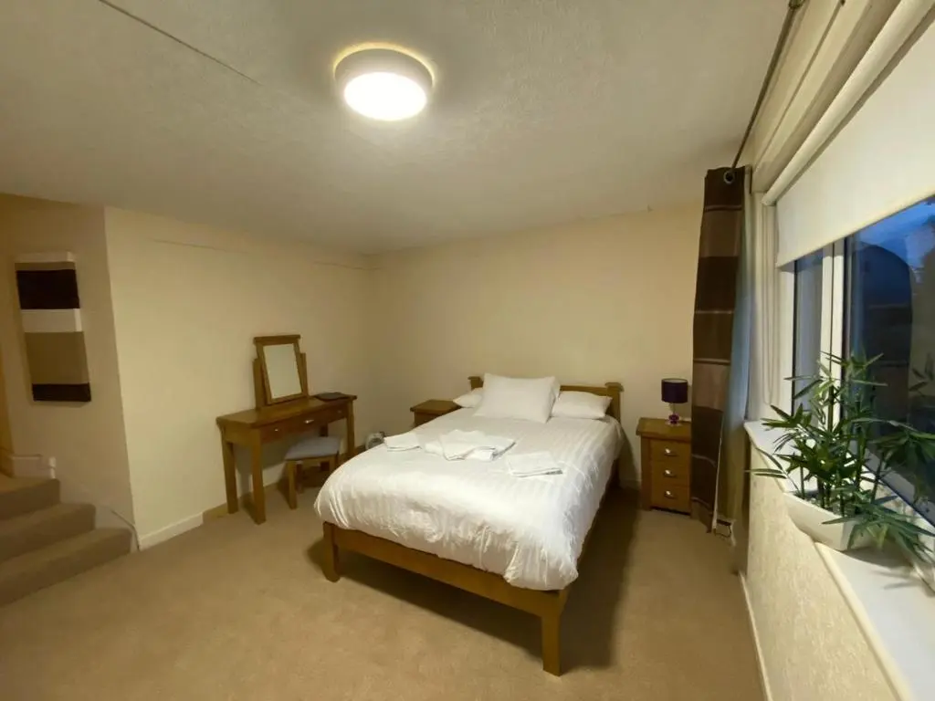 a bedroom with a bed and a table and a window at Inverness Holiday House in Dalneigh