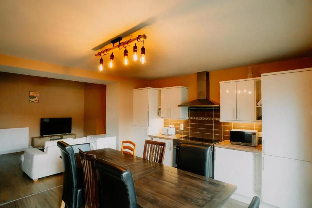 a kitchen with a wooden table and chairs and a kitchen with at Inverness Holiday House in Dalneigh