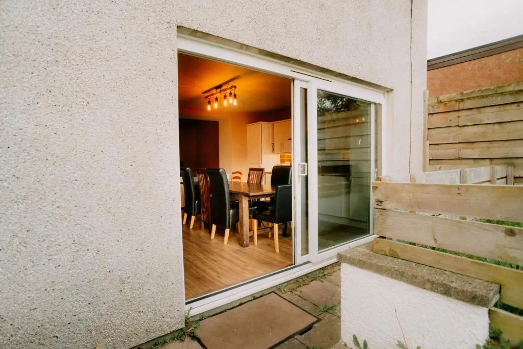 a sliding glass door to a dining room with a table at Inverness Holiday House in Dalneigh