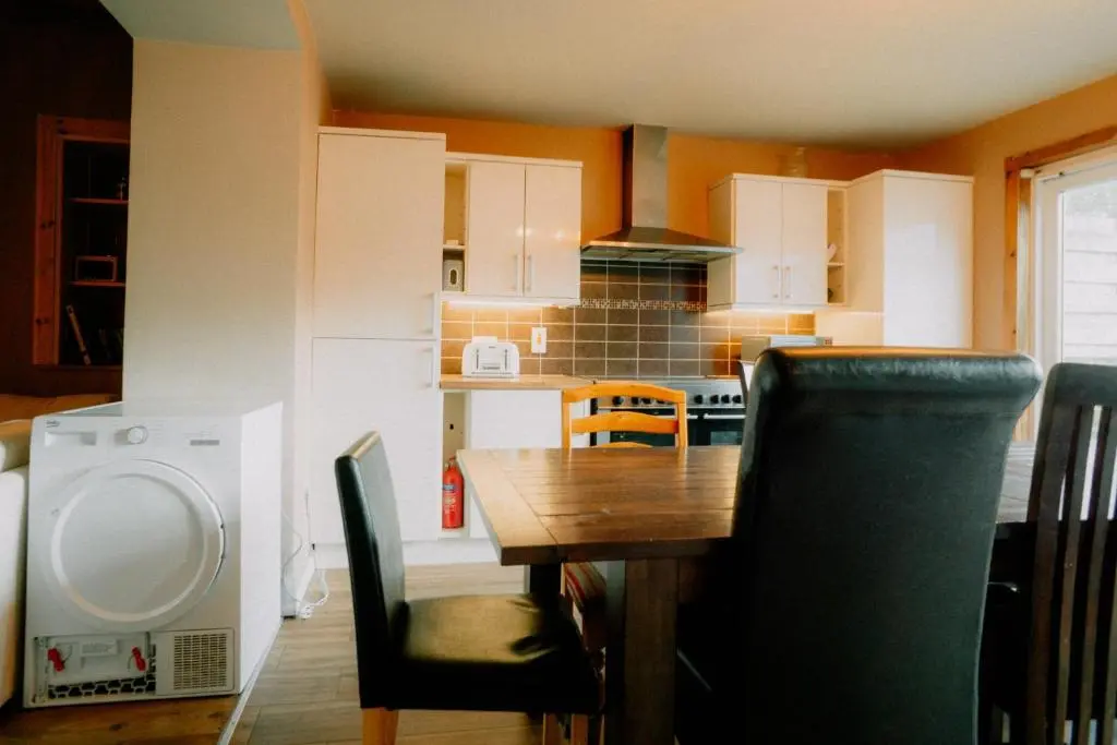 a kitchen with a wooden table and a dining room at Inverness Holiday House in Dalneigh