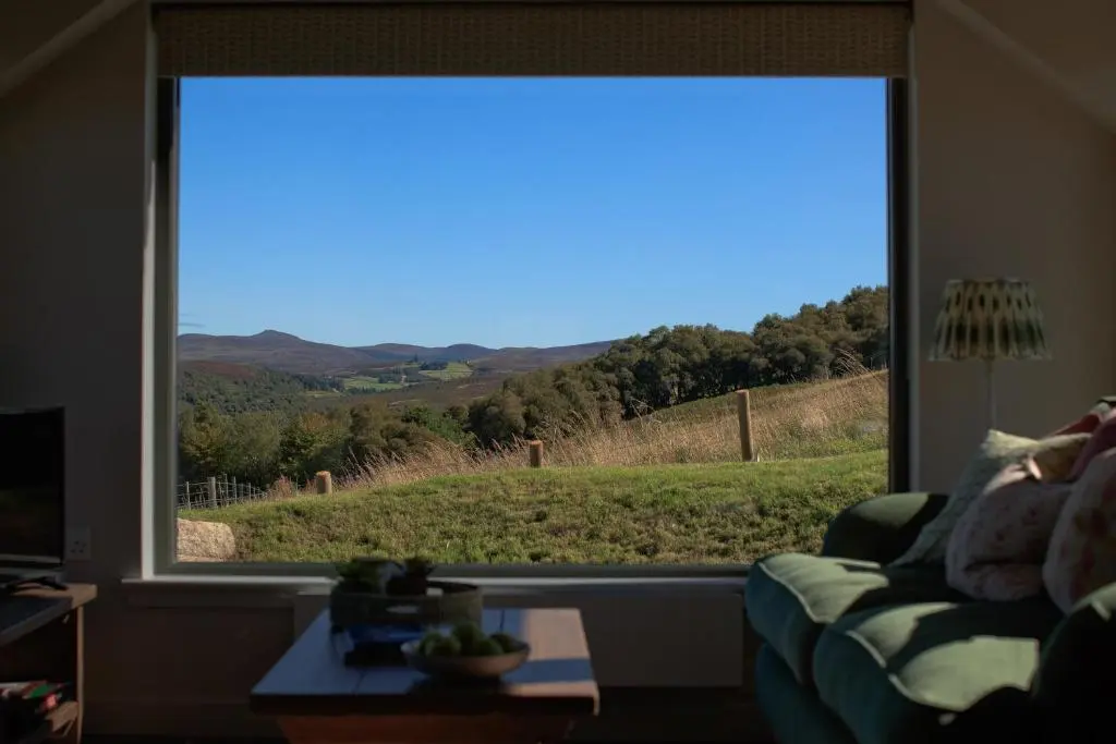 a living room with a large window looking out at a field at The Stable Bothy in Rogart