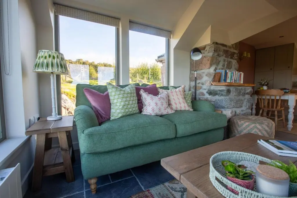 a living room with a green couch and a table at The Stable Bothy in Rogart