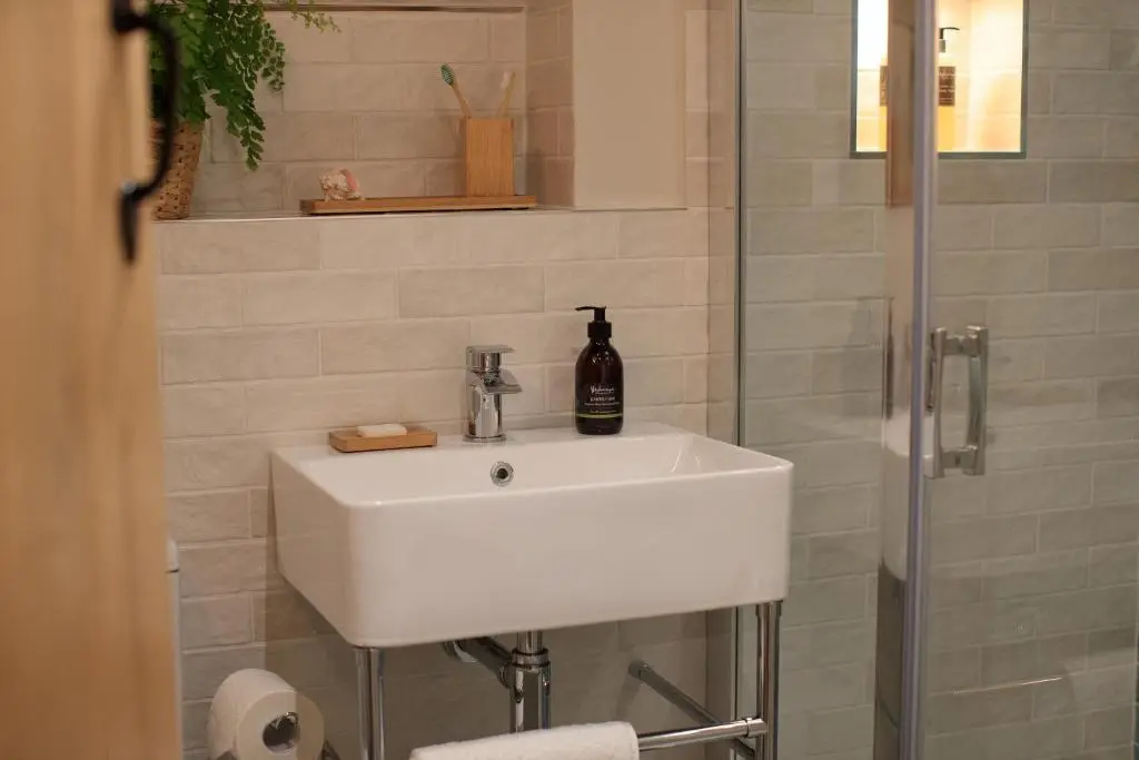 a bathroom with a white sink and a shower at The Stable Bothy in Rogart
