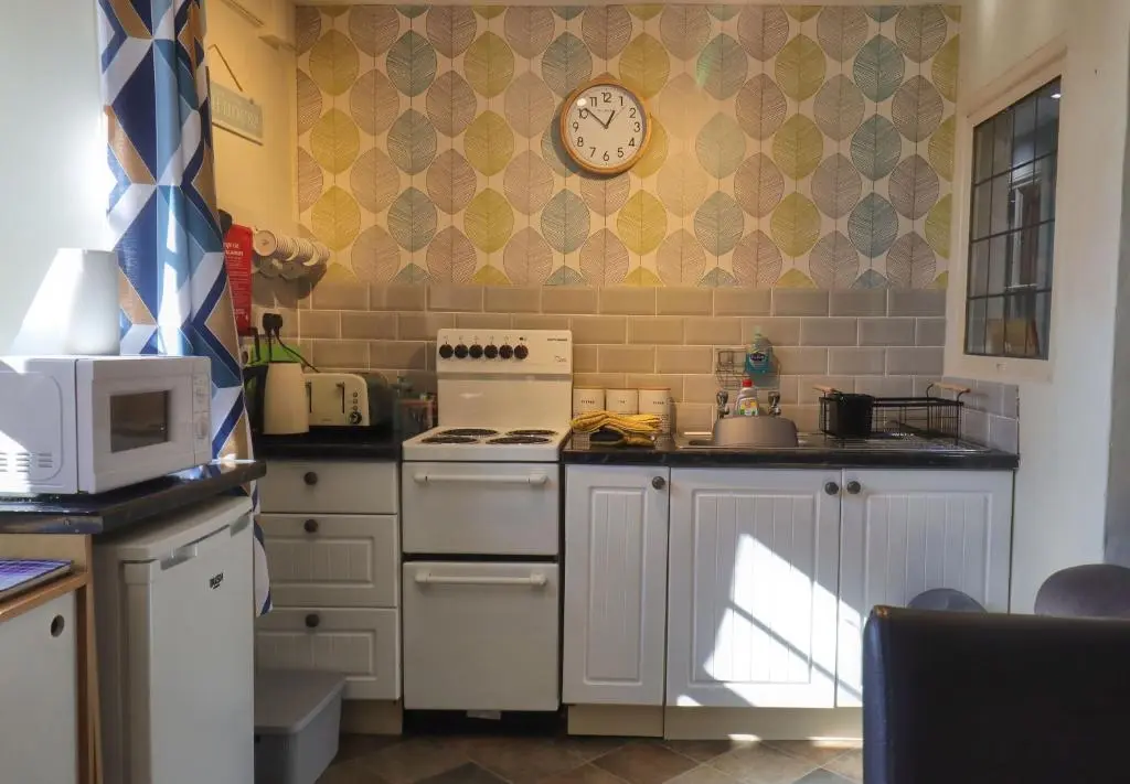 a kitchen with a stove and a clock on the wall at Fisherman's Rest in Helmsdale