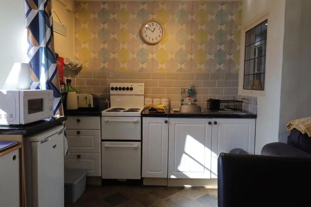 a kitchen with a stove and a clock on the wall at Fisherman's Rest in Helmsdale