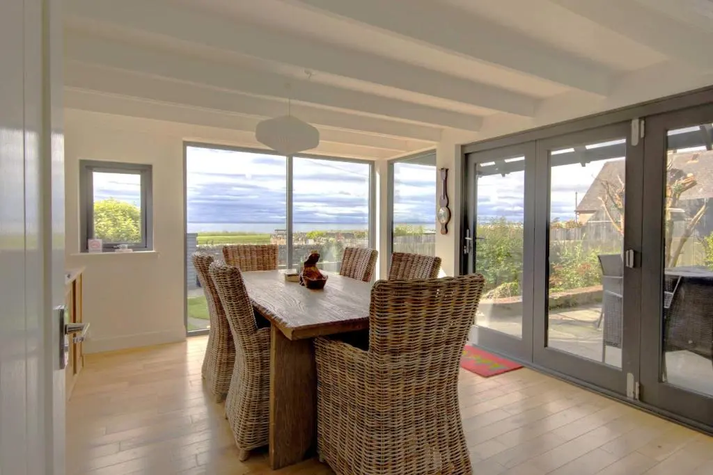 a dining room with a table and chairs and windows at Wilsons, Golspie in Golspie