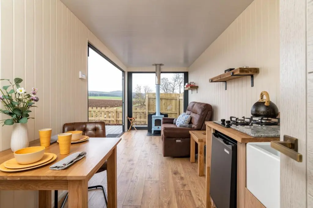 a kitchen and living room with a table and a stove at The Off Grid Cabin in Insch