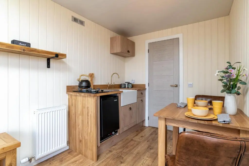 a kitchen with a table and a stove and a sink at The Off Grid Cabin in Insch