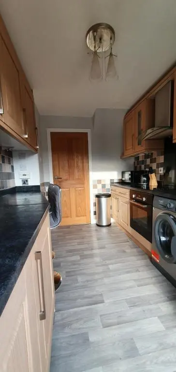 a kitchen with wooden cabinets and a stove top oven at York Street Retreat, modern cosy 2 bed with garden in Dufftown