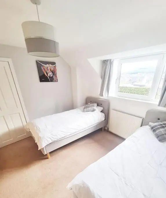 a bedroom with two beds and a window at York Street Retreat, modern cosy 2 bed with garden in Dufftown