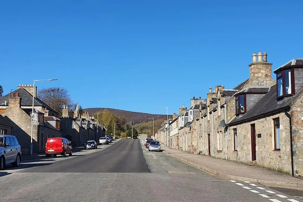 a street with rows of houses and cars parked on the road at York Street Retreat, modern cosy 2 bed with garden in Dufftown