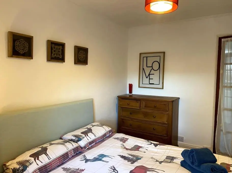 a bedroom with a bed and a wooden dresser at Historical North Cottage in Old Deer in Old Deer
