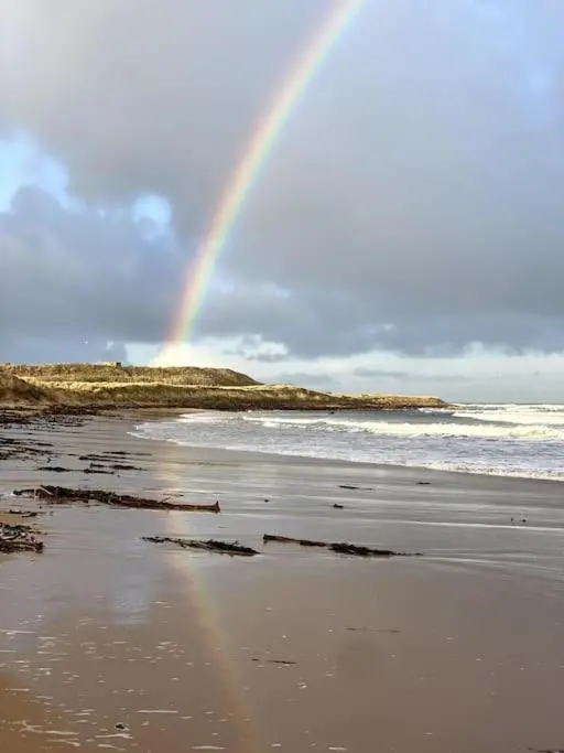 a rainbow over a beach with the ocean at Historical North Cottage in Old Deer in Old Deer