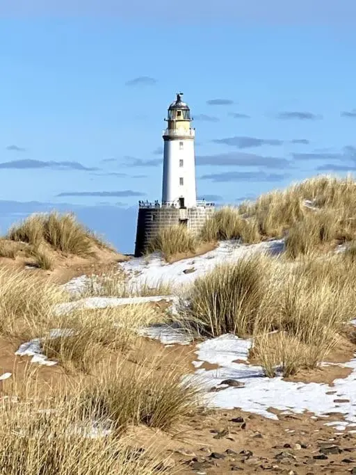 a lighthouse sitting on top of a grass covered hill at Historical North Cottage in Old Deer in Old Deer