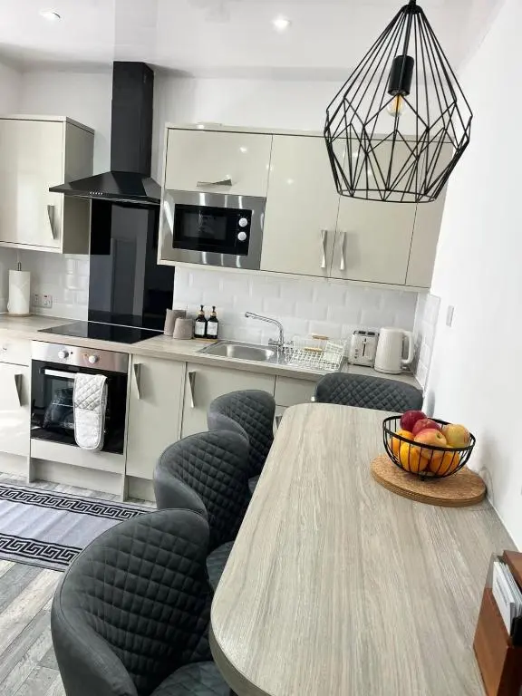 a kitchen with a table with chairs and a bowl of fruit at 39 Wells Street Apartment in Inverness