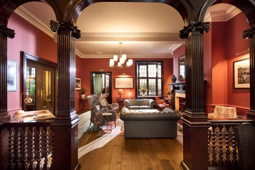 a living room with red walls and a couch and chairs at Royal Marine Hotel, by Highland Coast Hotels in Brora