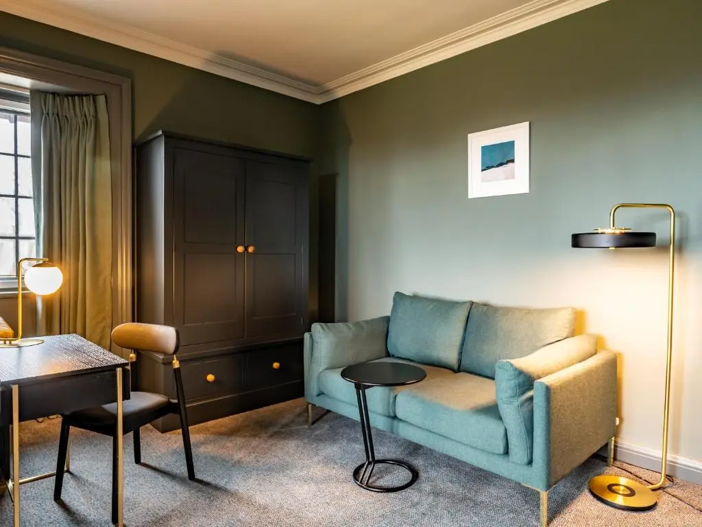 a living room with a blue couch and a table at Royal Marine Hotel, by Highland Coast Hotels in Brora