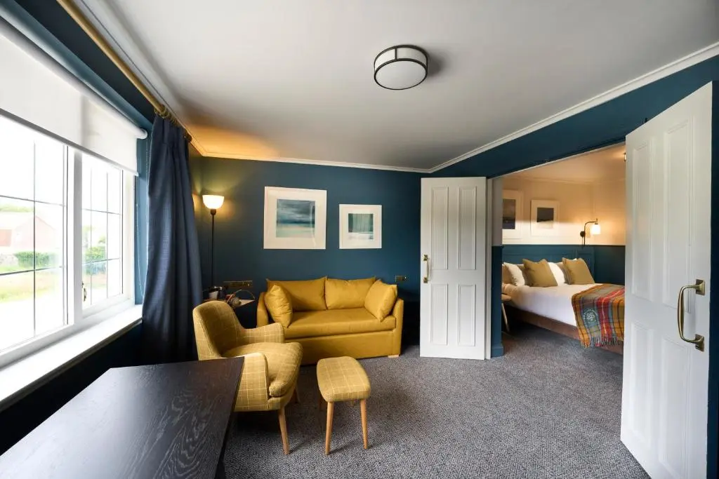 a room with a bedroom with a bed and a chair at Royal Marine Hotel, by Highland Coast Hotels in Brora