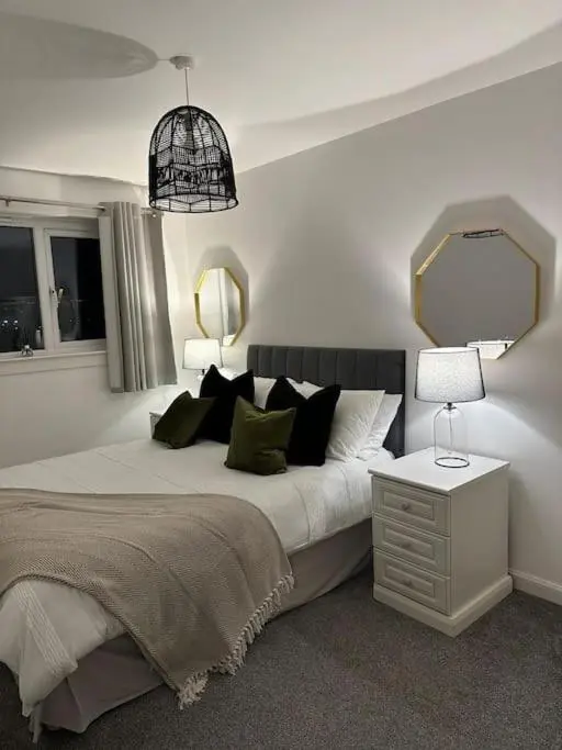 a bedroom with a large bed and a mirror at Stylish Highland Home in South Kessock