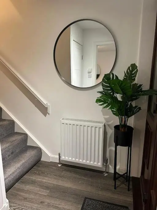 a hallway with a mirror and a plant and stairs at Stylish Highland Home in South Kessock