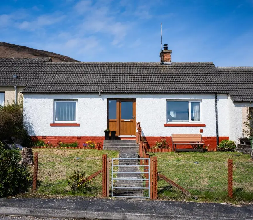a white house with a wooden door and stairs at North Coast Cottage - Coastal Highland Retreat with Sea Views in Portgower