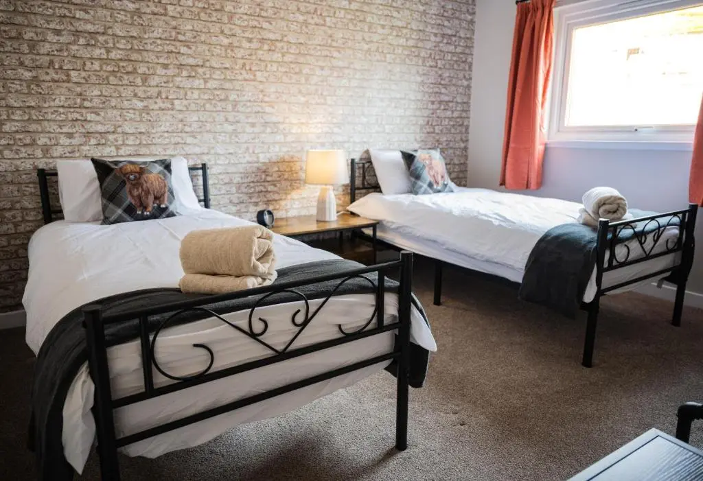 a room with two beds with a dog laying on them at North Coast Cottage - Coastal Highland Retreat with Sea Views in Portgower