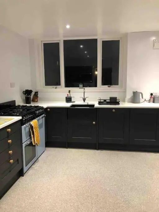 a kitchen with black cabinets and a stove and windows at Crannoch Self Catering - 10 bedroom former hotel in Cullen