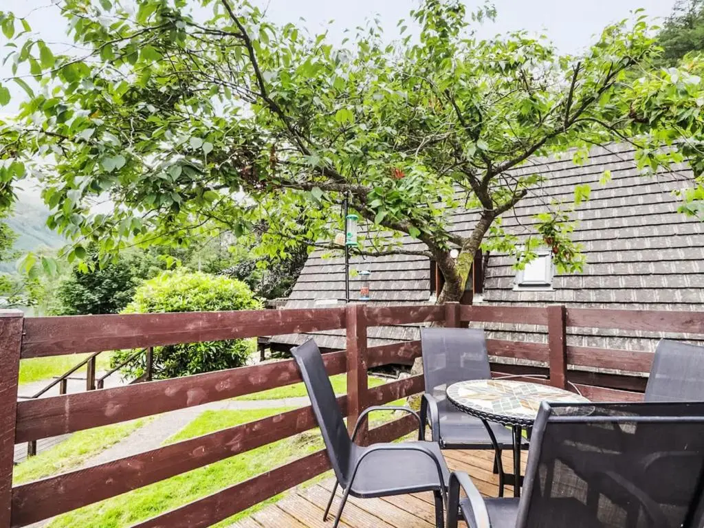 a patio with chairs and a table and a tree at Chalet Loch Lochy Retreat by Interhome in Spean Bridge
