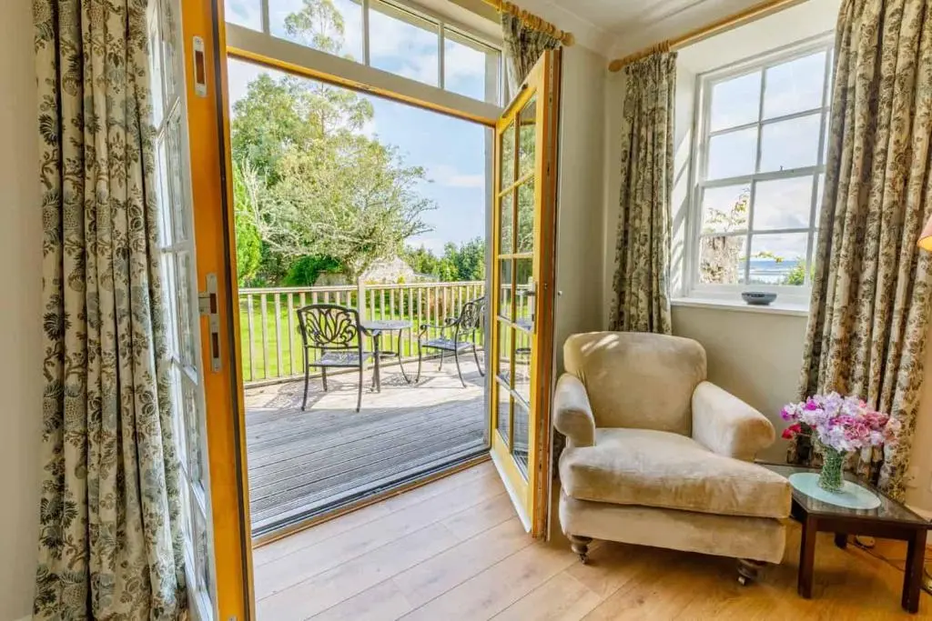a living room with a chair and a sliding glass door at Little Fyrish in Evanton