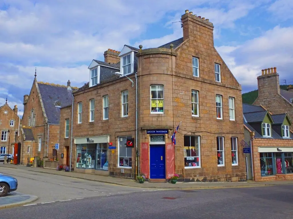 an old brick building with a blue door on a street at The Gordon Guest House in Ballater