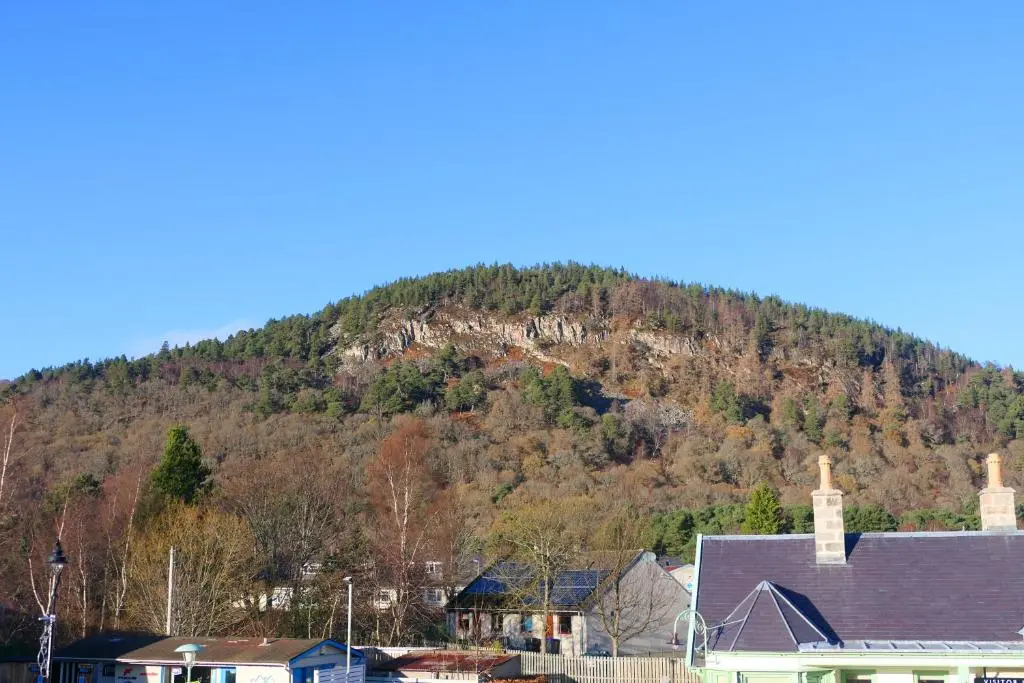 a mountain in the background of a town with houses at The Gordon Guest House in Ballater