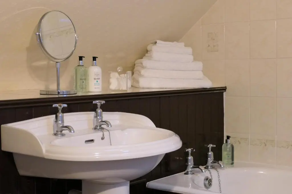 a bathroom with a sink and a mirror and a tub at The Gordon Guest House in Ballater