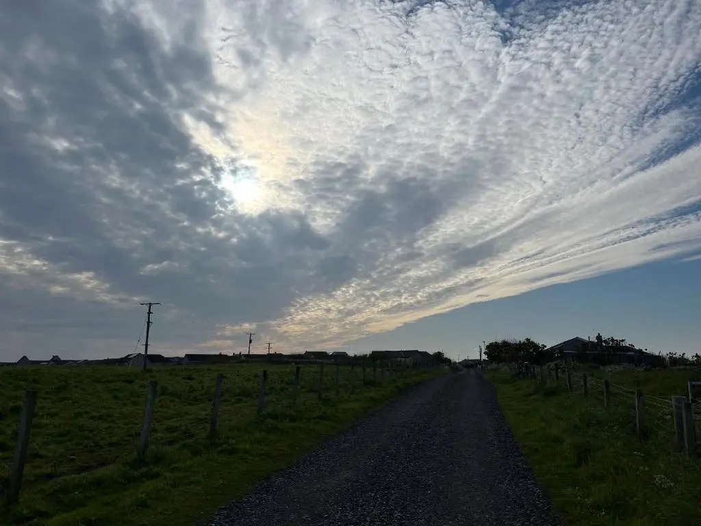 a dirt road in a field under a cloudy sky at Wee Coastal Snug in Wick
