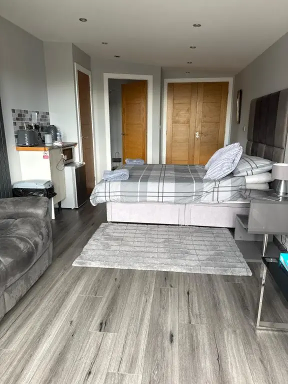 a bedroom with a large bed and a couch at Wee Coastal Snug in Wick