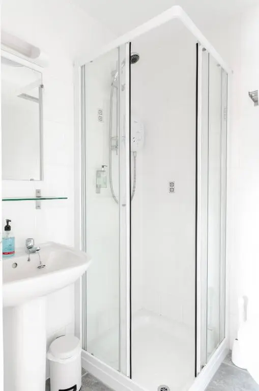 a white bathroom with a shower and a sink at Sweeney Aviemore Two in Aviemore