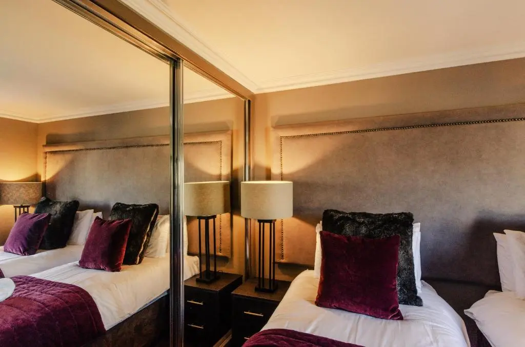 a hotel room with two beds and a mirror at Sweeney Aviemore Two in Aviemore