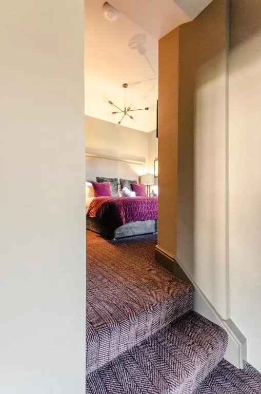 a bedroom with a bed with purple pillows at Sweeney Aviemore Two in Aviemore