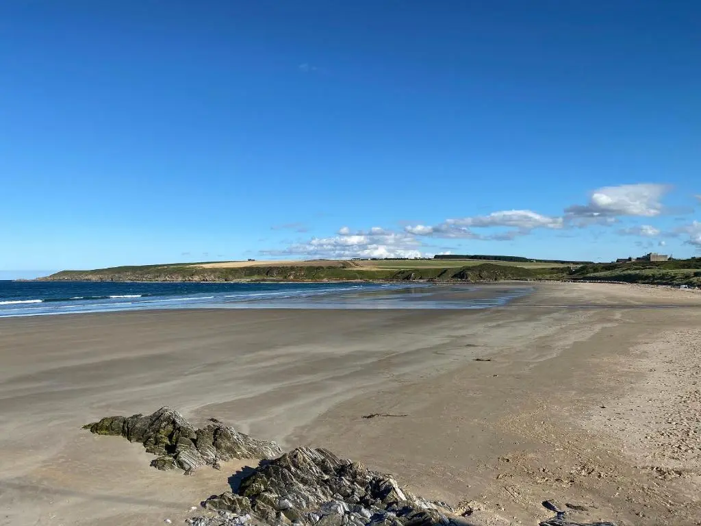 a beach with rocks in the sand and the ocean at The Brae Steading in Fordyce