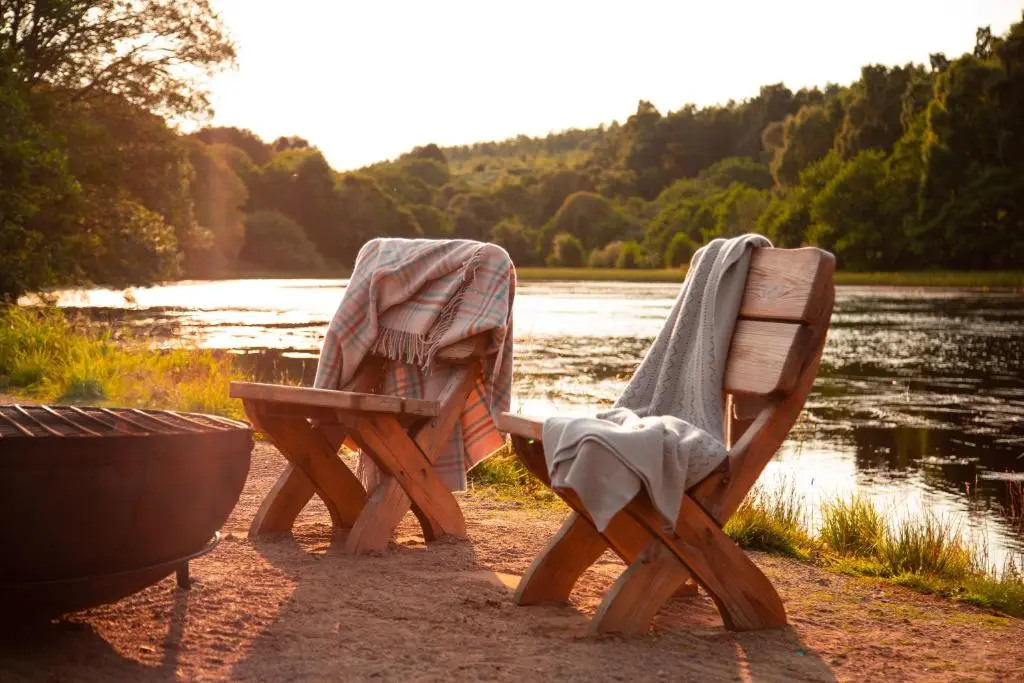 two wooden chairs sitting next to a body of water at Swiss Chalet Balnagown Castle in Kildary