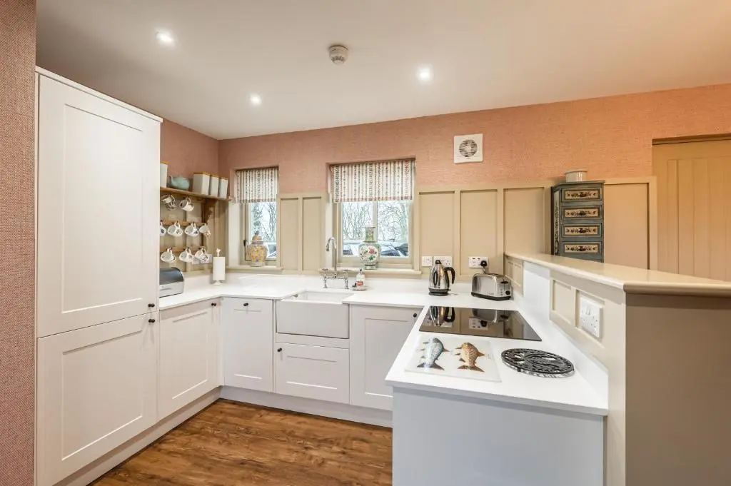 a kitchen with white cabinets and a stove top oven at Swiss Chalet Balnagown Castle in Kildary