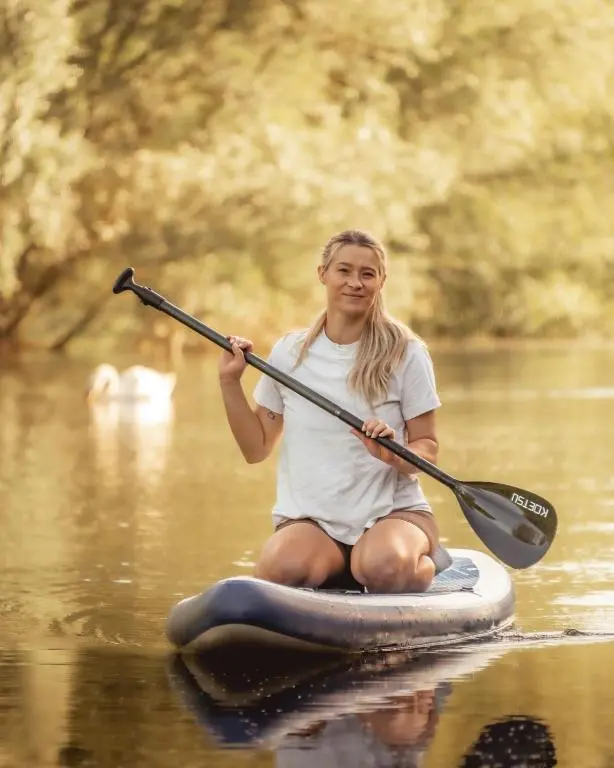 a woman sitting on a paddle board in the water at Swiss Chalet Balnagown Castle in Kildary