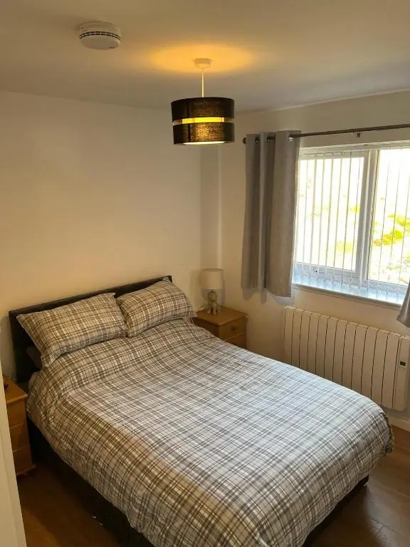a bedroom with a bed with a plaid blanket at Highland Holiday Lets Lairg in Lairg