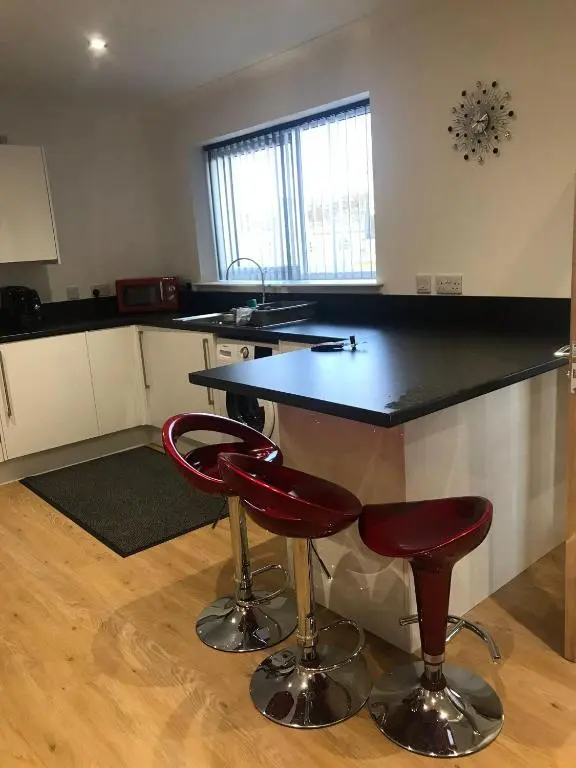 a kitchen with a black counter and two red bar stools at Highland Holiday Lets Lairg in Lairg