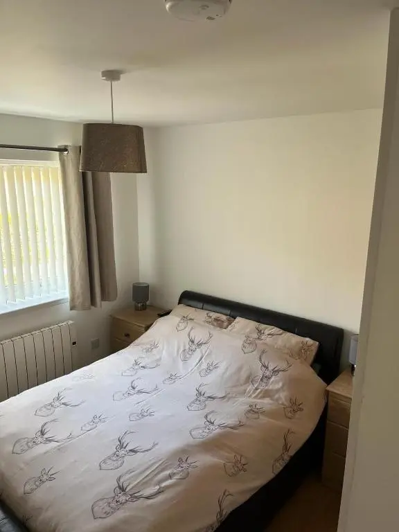 a bedroom with a bed with a white blanket at Highland Holiday Lets Lairg in Lairg