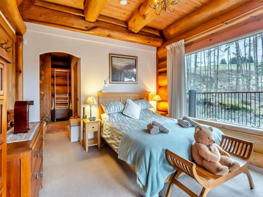 a bedroom with a teddy bear sitting on a bed at Molalatau Lodge in Lairg
