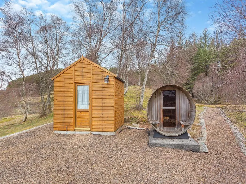 a small wooden cabin with a hobbit house next to it at Molalatau Lodge in Lairg